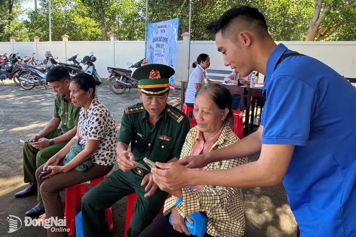 Cán bộ, chiến sĩ Đồn biên phòng Phước Thiện phối hợp các lực lượng hỗ trợ người dân xã Hưng Phước cài đặt mã quét QR "Hòm thư điện tử tố giác tội phạm". Ảnh: ĐVCC