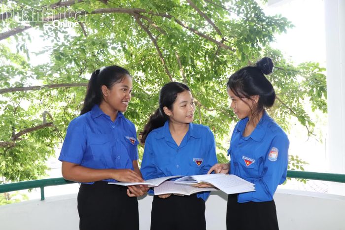 Em Pi Năng Thị Uyên (đứng giữa) trao đổi bài với các bạn trong giờ ra chơi.