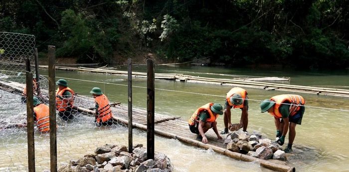 Lực lượng quân đội sử dụng bè mảng vận chuyển đá phục vụ xây dựng cầu tạm. (Ảnh: Đỗ Hoạt).