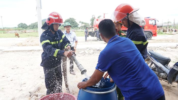 Người dân nhận nước sạch từ vòi chữa cháy. 