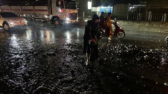 Mưa vẫn lớn và người dân gặp khó khăn đi qua chỗ đá to như cườm tay tràn ra đường.