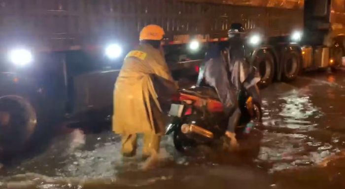 Cảnh sát giao thông Trạm Đa Phước hỗ trợ người dân điều khiển xe máy qua chỗ nước ngập.