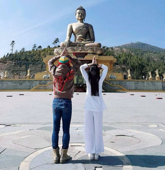 Tuấn Hưng đăng ảnh cùng vợ chắp tay trước tượng Phật.