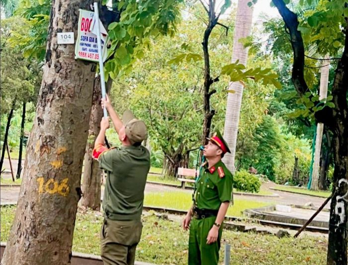 Công an phường Việt Hưng bóc gỡ tờ rơi quảng cáo được treo, dán trái phép. Ảnh: PV
