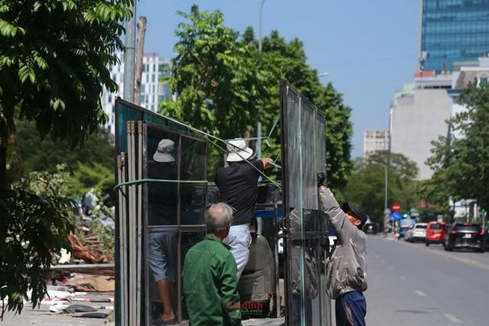 Tại hiện trường người dân thu dọn những tấm kính lớn, khung cửa đã được tháo dỡ đang chuẩn bị di chuyển rời khỏi khu vực vi phạm.