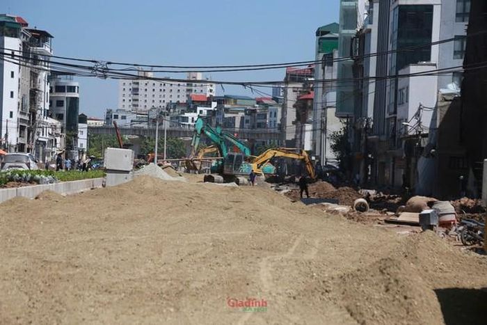 Máy xúc cùng các thiết bị chuyên dụng thi công liên tục sát khu vực nhà dân và các tòa chung cư cao tầng ven tuyến đường.