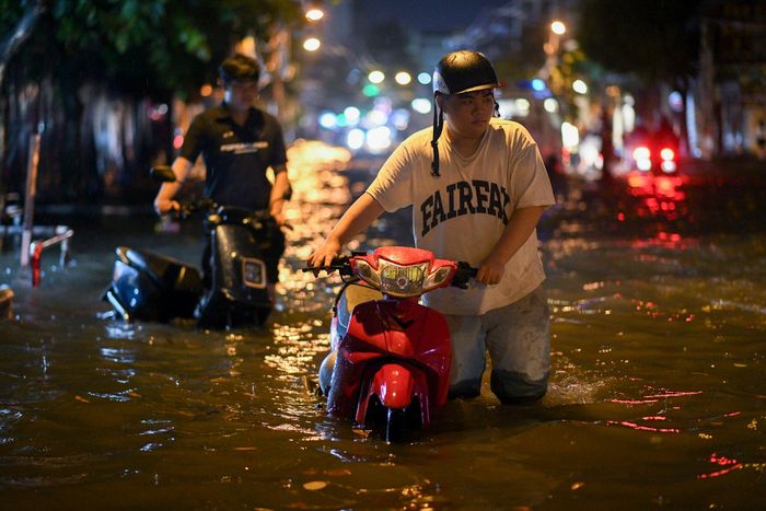  Văn Hưng, nhân viên một nhà hàng trên đường Lê Văn Thọ, dắt xe ra khỏi bãi sau khi tan làm tối 7/10. "Nước ngập vào trong bãi xe, em cũng không biết xe còn đi được không, dắt qua đoạn ngập rồi mới dám nổ máy", Hưng nói. 