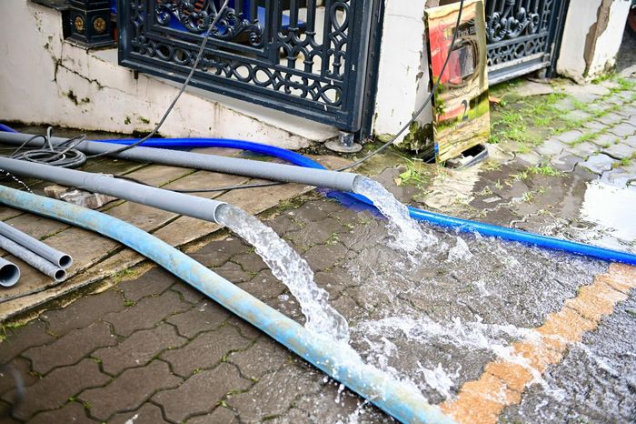 Bà Hường cùng nhân viên dọn dẹp vật dụng sau khi dùng máy bơm rút nước khỏi tầng hầm sáng 8/10. Ảnh: Hoài Bảo. 