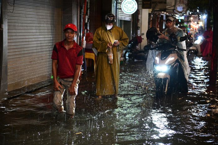 Người dân di chuyển khó khăn vì đường ngập sau cơn mưa lớn tối 7/10. Ảnh: Hoài Bảo. 