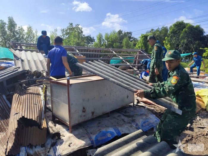 Cán bộ, chiến sĩ Đồn Biên phòng Đất Mũi hỗ trợ người dân dựng lại nhà sau dông lốc. Ảnh: CÔNG XUÂN