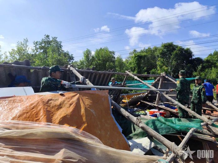 Cán bộ, chiến sĩ Đồn Biên phòng Đất Mũi hỗ trợ người dân dựng lại nhà sau dông lốc. Ảnh: CÔNG XUÂN