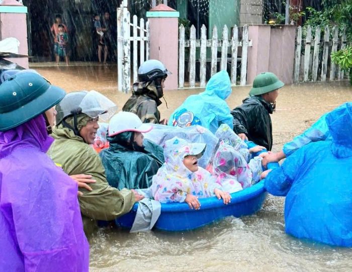  Lực lượng dùng thuyền thúng đưa học sinh đến nơi an toàn. Ảnh: KỲ HÀ 
