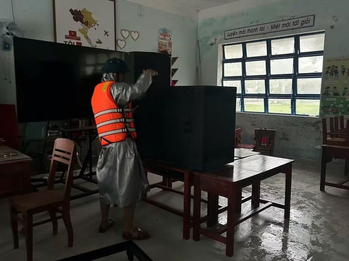 Hỗ trợ trường học kê cao đồ đạc tránh hư hỏng do ngập lụt. Ảnh: Sông Hàn