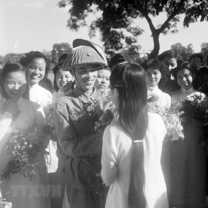 Thiếu tướng Vương Thừa Vũ, Tư lệnh Đại đoàn 308, Chủ tịch Ủy ban Quân chính Thành phố nhận hoa chúc mừng từ các nữ sinh trường Trưng Vương bên Hồ Hoàn Kiếm trong ngày giải phóng Thủ đô. Ảnh: Tư liệu TTXVN