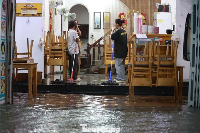 Một số chủ cửa hàng đứng trước cửa, dùng nệm, cây gạt nước và các vật dụng khác để ngăn nước tràn vào.