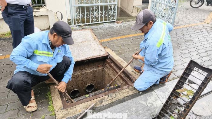 Công nhân khẩn trương xử lý hệ thống cống thoát nước, nhằm đẩy nhanh tốc độ rút nước tại khu vực bị ngập.