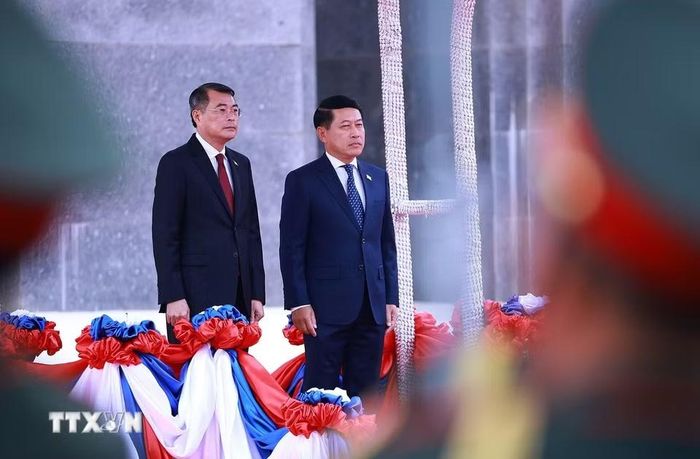 Thủ tướng Lê Minh Hưng và Thủ tướng Saleumxay Kommasith nghe Quân nhạc cử Quốc thiều hai nước. (Ảnh: Dương Giang/TTXVN)