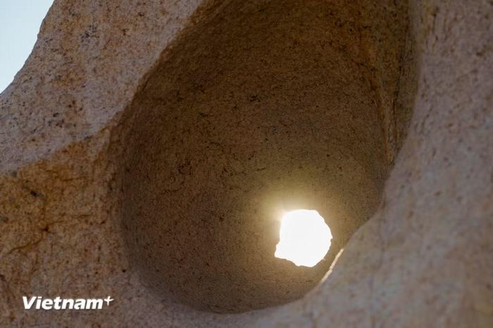 Ánh nắng lọt qua một lỗ hổng trên phiến đá, tạo nên khung cảnh nghệ thuật. Bình minh và hoàng hôn là hai thời điểm đẹp nhất để chiêm ngưỡng vẻ rực rỡ của đá tại đây. (Ảnh: Thanh Phong/Vietnam+)
