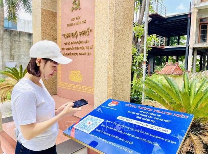 Du khách đến từ tỉnh Đắk Lắk trải nghiệm quét mã QR tại di tích nơi thành lập “Chi bộ phố” tỉnh Quảng Trị (Chi bộ Đảng Cộng sản Việt Nam đầu tiên của thị xã Đồng Hới được thành lập). Ảnh: Võ Dung/TTXVN.