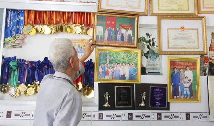 Ông của Ánh Viên chụp ảnh bên cạnh những thành tích của cháu gái. Ảnh: Huỳnh Xây