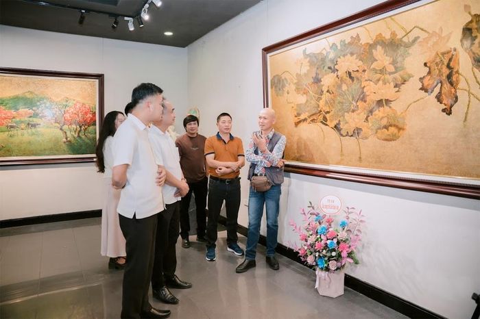  Họa sĩ Trần Trung giới thiệu tác phẩm với đại biểu tham quan triển lãm. 