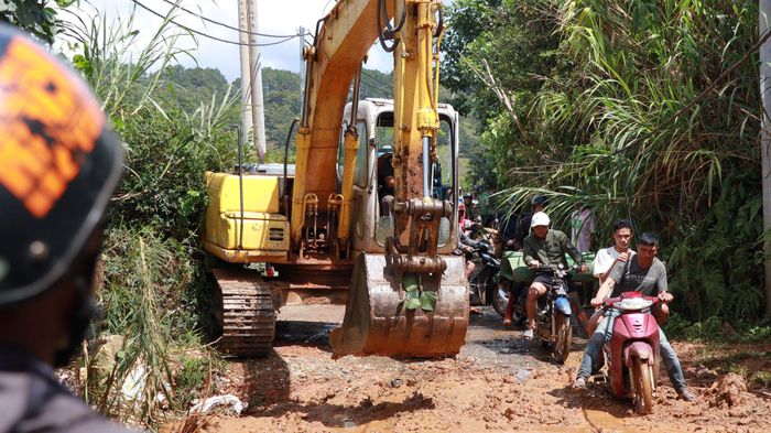Người dân huy động xe múc san gạt tuyến đường, khơi thông dòng chảy để thoát nước và đi lại dễ dàng hơn