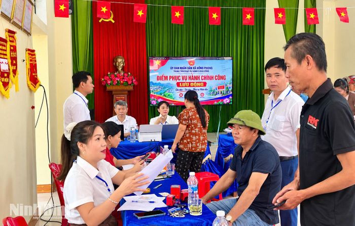 Người dân thôn 12, xã Hồng Phong được cán bộ hướng dẫn, hỗ trợ thực hiện thủ tục hành chính ngay tại Nhà văn hoá thôn.