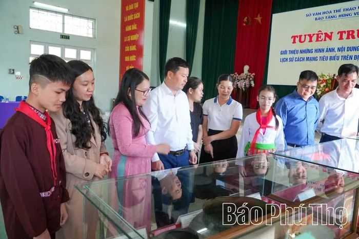 Cán bộ, giáo viên và các em học sinh nghe giới thiệu về các hiện vật.