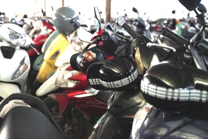Những chiếc mũ giá rẻ, không dành cho người đi mô tô, xe máy, xuất hiện trên nhiều xe máy tại các bãi gửi xe trường học ở Hà Nội.