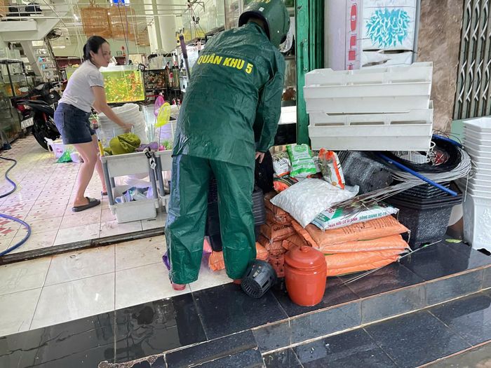 Lực lượng chức năng kịp thời hỗ trợ người dân đưa nhu yếu phẩm đến nơi cao ráo.