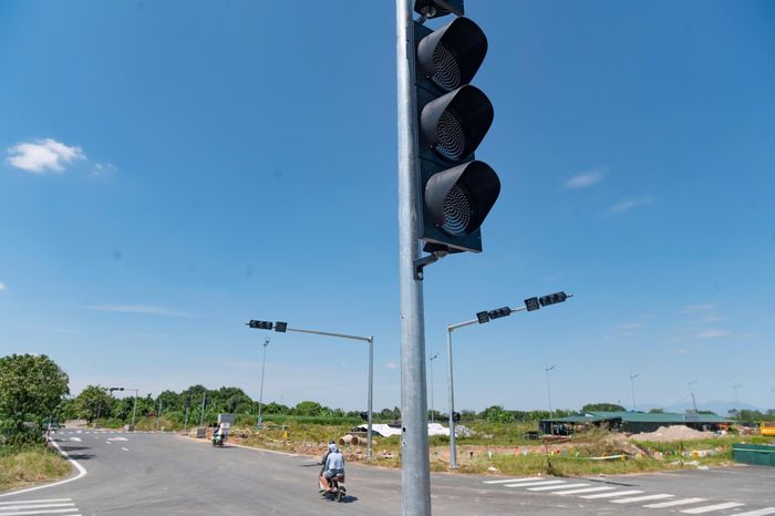 Ông Nguyễn Văn Hùng, người dân khu vực Hoài Đức, cho biết việc đi lại giữa các khu vực thời gian qua còn phụ thuộc nhiều vào các tuyến đường hiện hữu, trong khi vào giờ cao điểm thường xảy ra ùn tắc. Theo ông Hùng, tuyến đường mới sẽ giúp người dân có thêm lựa chọn di chuyển, nhất là khi kết nối với Đại lộ Thăng Long và các tuyến đường lớn. “Chúng tôi mong tuyến sớm được đưa vào khai thác để việc đi lại thuận tiện hơn”, ông Hùng chia sẻ. Trong ảnh, cùng với việc hoàn thiện mặt đường, các hạng mục như hệ thống chiếu sáng, vạch kẻ đường và rào chắn an toàn đang được gấp rút triển khai. Tại các nút giao, đèn tín hiệu giao thông đã được lắp đặt, sẵn sàng đưa vào vận hành khi tuyến đường khai thác.