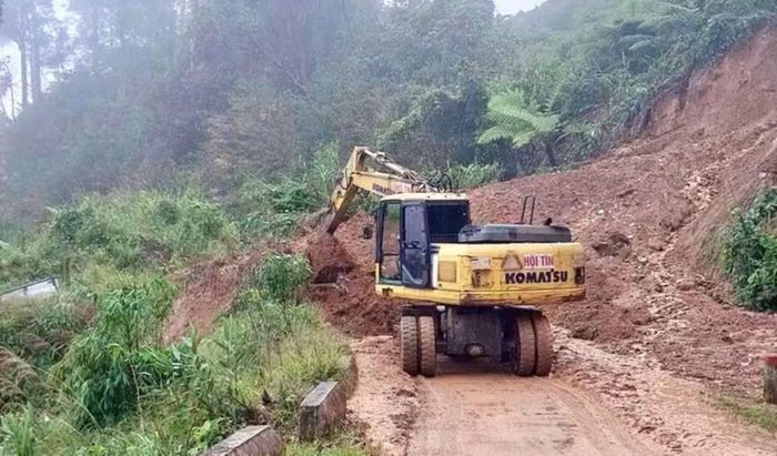 Xe múc nỗ lực dọn dẹp đất đá sạt trượt để thông tuyến đường sạt lở tại xã Trà Linh.