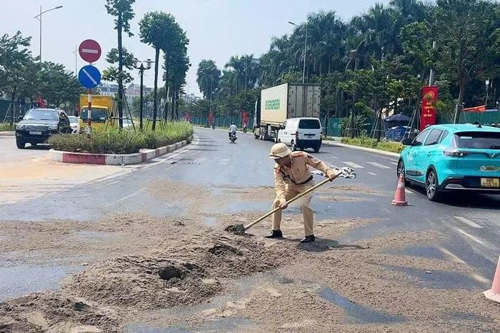 Cán bộ CSGT rải cát khắc phục tình trạng trơn trượt trên đường.