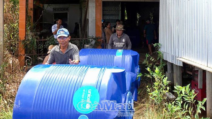 Người dân xã Khánh Lâm phấn khởi nhận bồn chứa nước được hỗ trợ.