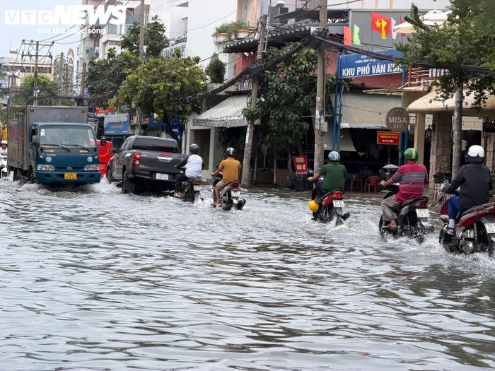 Nước ngập từ lòng đường tràn lên vỉa hè đường Nguyễn Văn Khối, khiến người đi bộ không còn nhiều khoảng trống để tránh dòng phương tiện và nước dồn từ mặt đường.