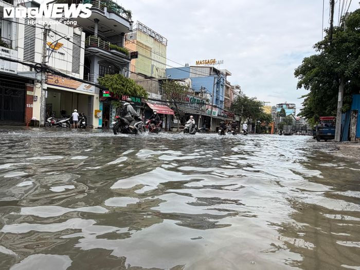 Nước ngập phủ mặt đường trong nhiều giờ, khiến người đi xe máy phải tìm cách vượt qua những đoạn nước sâu.