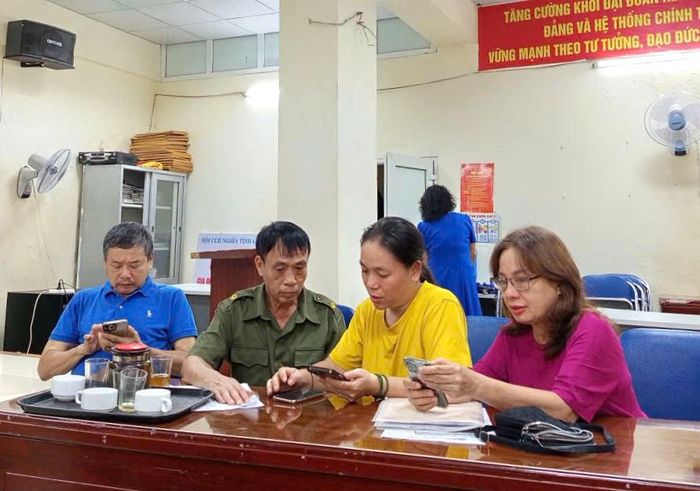 Cán bộ Tổ chuyển đổi số cộng đồng, Tổ dân phố số 12 phường Bạch Mai hỗ trợ người dân cài đặt ứng dụng iHanoi, VNeID. Ảnh: PV