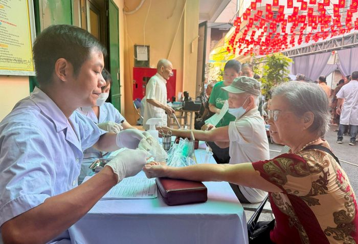 Nhân viên y tế Bệnh viện Đa khoa Xanh Pôn lấy mẫu máu xét nghiệm cho người dân tại chương trình. Ảnh: H.Duy