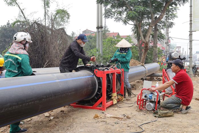 Công nhân Công ty Môi trường đô thị Xuân Mai lắp đặt tuyến ống truyền dẫn nước sạch từ xã Xuân Mai về phường Chương Mỹ. Ảnh: Kim Nhuệ