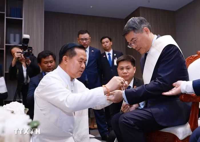 Thủ tướng Lê Minh Hưng thực hiện nghi thức buộc chỉ cổ tay truyền thống của Lào.