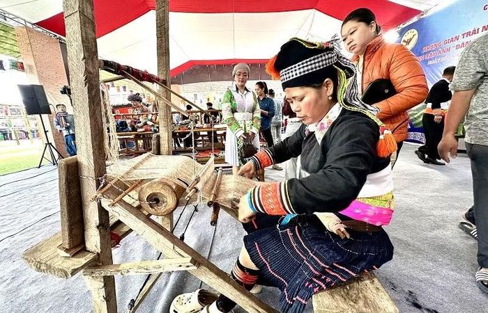Giữa không gian Ngày hội sôi động, người phụ nữ dân tộc Mông miệt mài bên khung dệt. (Ảnh: LÊ LAN)