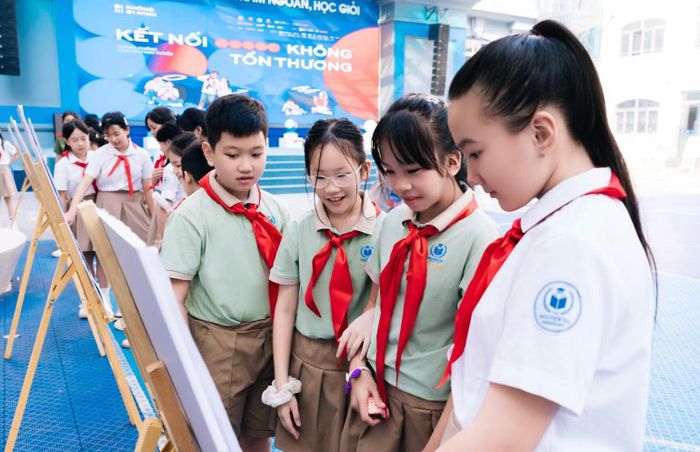 Các học sinh Trường trung học cơ sở và Trung học phổ thông Nguyễn Siêu tham quan triển lãm tranh cổ động Chiến dịch "Không một mình". (Ảnh: Ban tổ chức cung cấp)