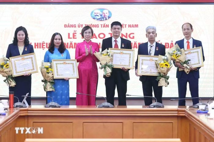 Đồng chí Vũ Việt Trang, Ủy viên Ban Thường vụ Đảng ủy các cơ quan Đảng Trung ương, Bí thư Đảng ủy, Tổng Giám đốc Thông tấn xã Việt Nam, Phó Trưởng ban Tuyên giáo Trung ương trao Huy hiệu cho các đồng chí 40 năm; 35 năm và 30 năm tuổi Đảng. (Ảnh: An Đăng/TTXVN)