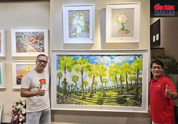 Khách tham quan lưu lại khoảnh khắc bên những tác phẩm giàu màu sắc tại triển lãm tranh của họa sĩ Phạm Văn Kiệm.