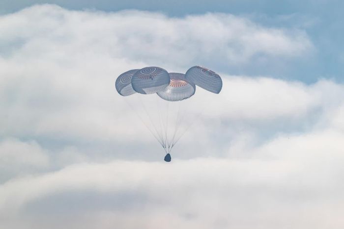 Tàu vũ trụ SpaceX sử dụng dù để hạ cánh xuống Thái Bình Dương ngoài khơi bờ biển California. Ảnh: Keegan Barber/NASA qua AP