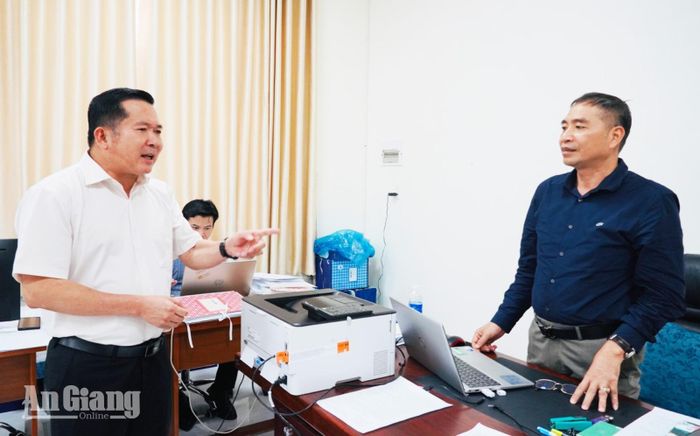 Đồng chí Đinh Văn Nơi (bên trái) chỉ đạo cán bộ Tổ cấp giấy chứng nhân quyền sử dụng đất.