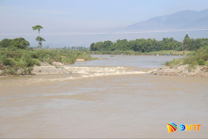 Công trình đập tạm trên sông Quảng Huế mới chỉ được gạt một phần bề mặt cho nước chảy qua chứ chưa tháo dỡ hoàn toàn, nhằm chủ động ứng phó với tình trạng nước sông hạ thấp trong mùa El Nino có cường độ rất mạnh. Ảnh: HOÀNG HIỆP