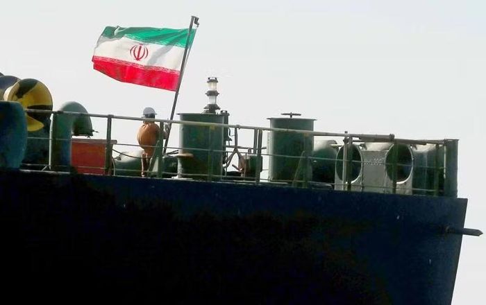 Một thành viên thủy thủ đoàn kéo cờ Iran lên tàu chở dầu. Ảnh: Reuters