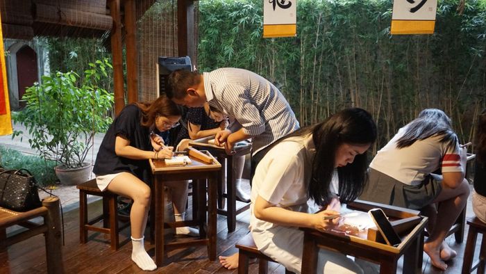 Nghệ nhân Đỗ Trọng Quân (áo kẻ) tận tình hướng dẫn các bạn trẻ trải nghiệm workshop