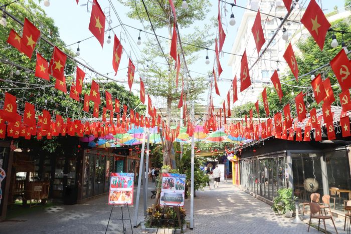 Phố Sách Hà Nội được trang hoàng rực rỡ với hàng trăm lá Quốc kỳ, cờ Đảng kết hợp cùng không gian xanh rợp bóng mát.